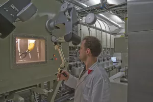 An employee processes a sample for the rabbit irradiation system using a manipulator. (Photo: W. Schürmann / TUM)